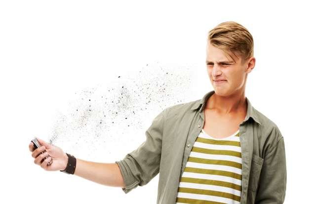 Studio shot of a young man holding a cellphone and reacting to a text message isolated on white