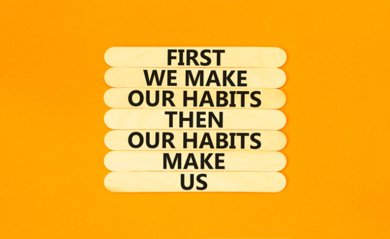 Our habits symbol. Concept words First we make our habits then our habits make us on wooden stick. Beautiful orange table orange background. Copy space. Motivational business our habits concept.